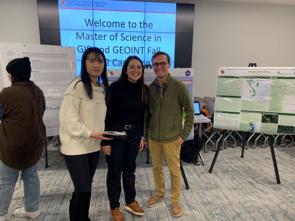 Three MS students smile in front of their posters