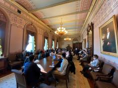 Meeting attendees seated at a long, rectangular table in a room in the White House